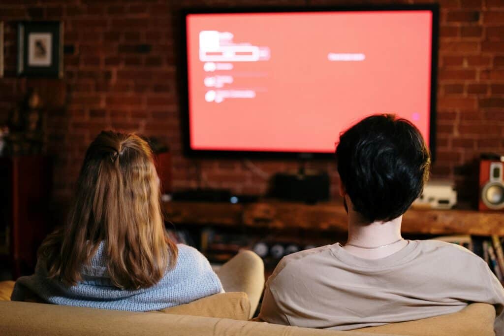 A couple is watching TV in the living room of their flat