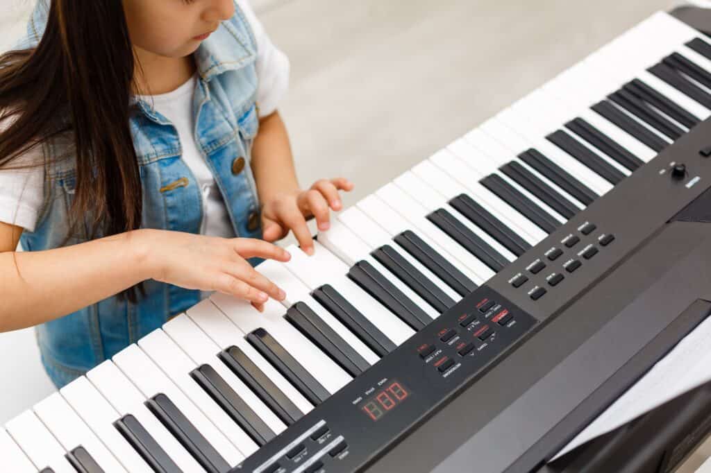 Cropped image of a young female student playing the piano in a music class